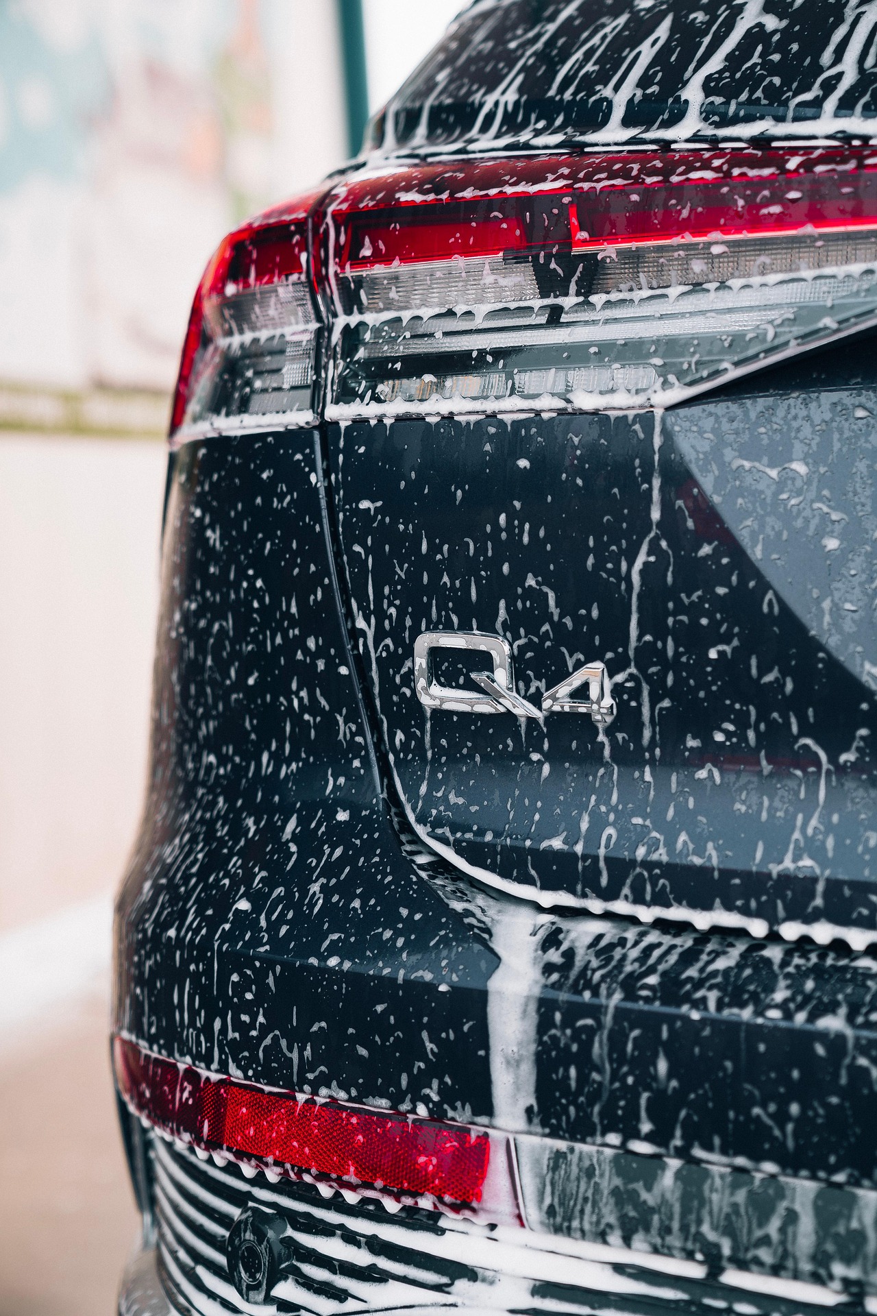 lavage exterieur labo detailing A detailed shot of a car headlight covered in water droplets, showcasing automotive design.